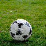 Close-up of a classic soccer ball resting on a lush green field.
