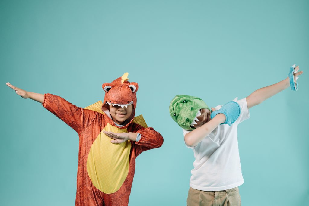 Two kids in dinosaur costumes enjoying playtime and having fun.