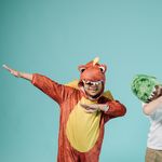 Two kids in dinosaur costumes enjoying playtime and having fun.